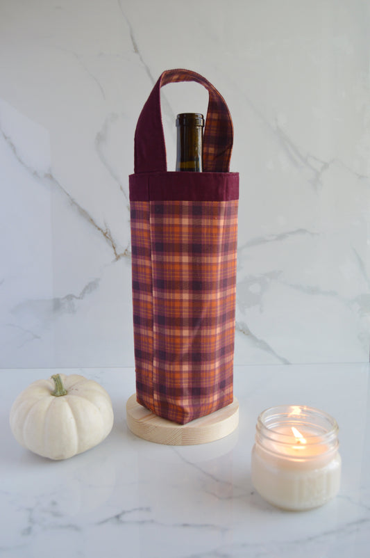 fall wine bottle bag with burgundy fall design next to pumpkin and candle