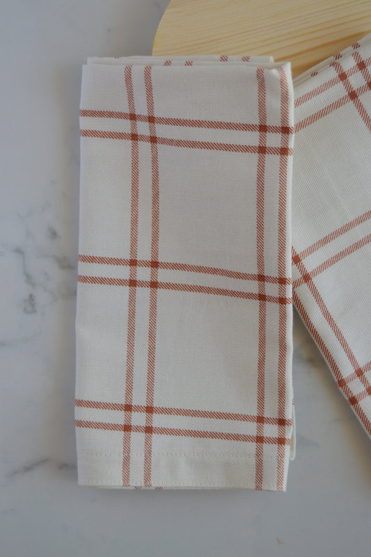 close up photo of light tan plaid napkin with rust orange accent